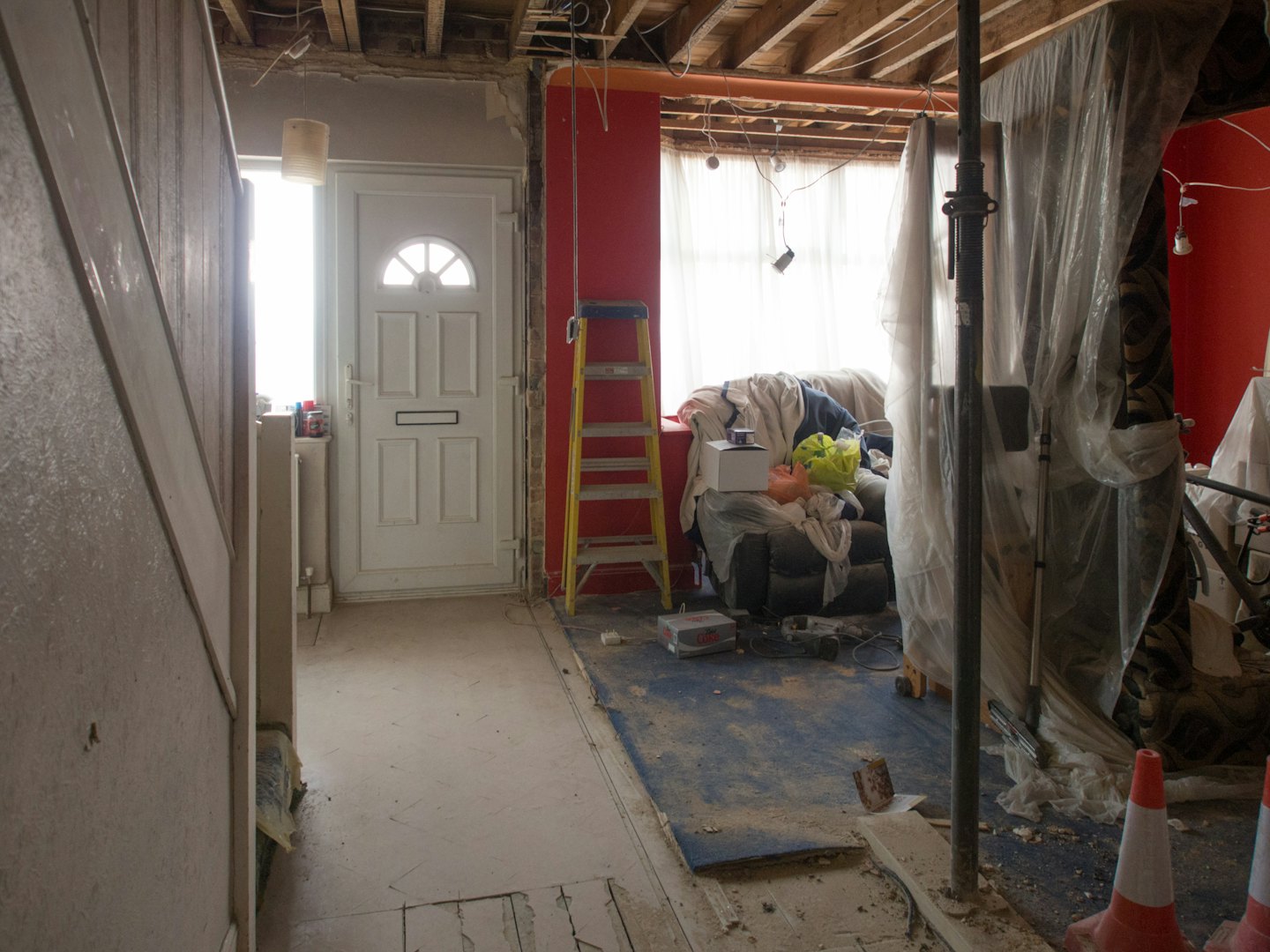 Home renovation with exposed beams, red walls, and debris.